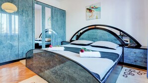 A modern bedroom with a curved bed, a large mirror, and a decorative painting on the wall.