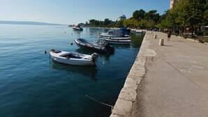 A waterfront promenade with boats docked along the edge.