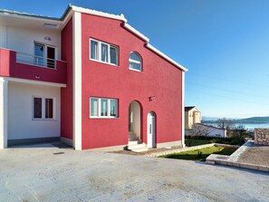 Ένα διώροφο σπίτι με κόκκινη πρόσοψη, λευκά παράθυρα και ένα μικρό μπαλκόνι.