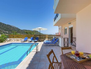 A poolside area with lounge chairs and a table with breakfast items. - Hillside Villa in Bali With Private Pool (Mylopotamos)