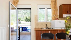 A kitchen with a dining area, a view of the outdoors, and a white refrigerator. - Hillside Villa in Bali With Private Pool (Mylopotamos)