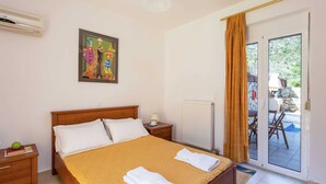 A bedroom with a bed, a nightstand, a radiator, a painting, and a view of the outside through a sliding door. - Hillside Villa in Bali With Private Pool (Mylopotamos)