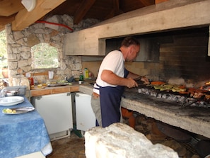 Outdoor kitchen with brick oven, sink, and refrigerator, perfect for casual dining.