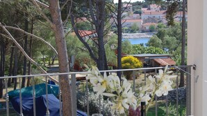 A balcony with a table set for dining, overlooking a scenic view of trees and buildings.