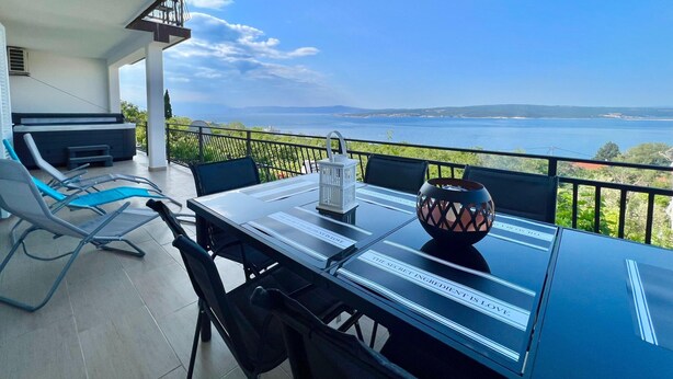 Ein Balkon mit Tisch, Stühlen und Meerblick.