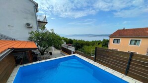 Una piscina con vistas al mar, rodeada de edificios y follaje.