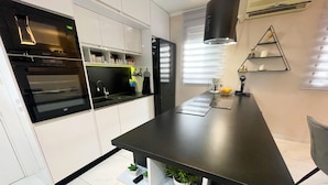 Una cocina moderna con armarios blancos, encimera negra y plantas integradas.