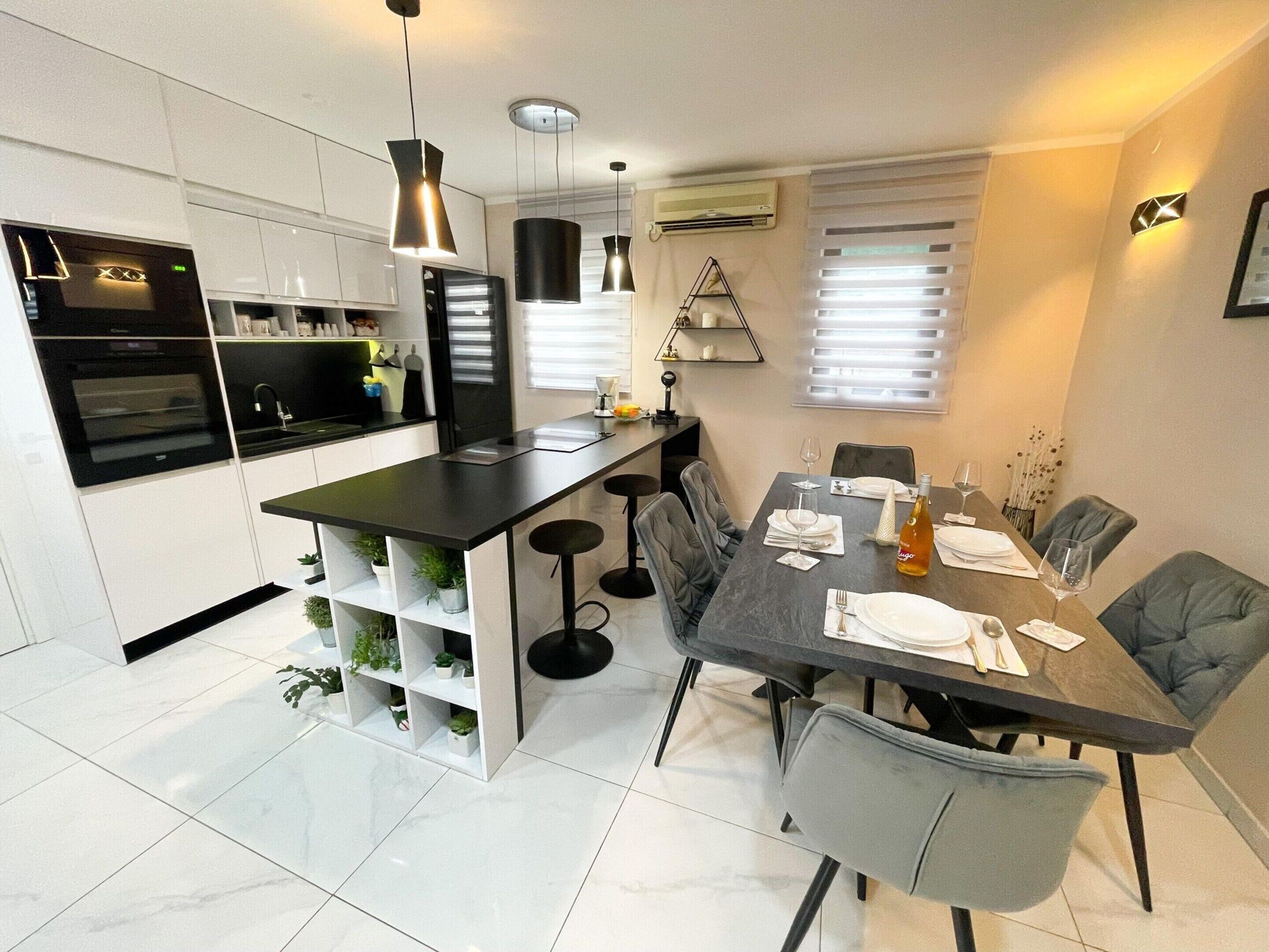 Una cocina moderna con una isla central, taburetes de bar y una mesa de comedor para cuatro.