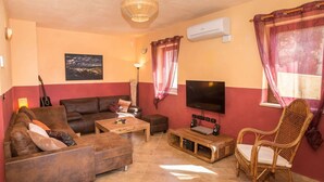 A living room with a sofa, coffee table, TV, speakers, and a wicker chair. - Adorable Holiday Home With Private Swimming Pool & Terrace (Visnjan)