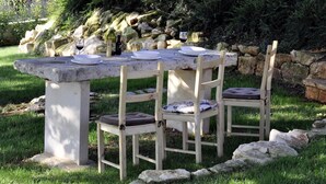 An outdoor stone table with chairs, set in a garden with a stone wall and greenery in the background. - Adorable Holiday Home With Private Swimming Pool & Terrace (Visnjan)