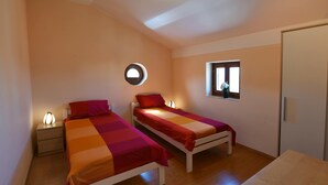 A small, well-lit room with two single beds, a bedside table with a lamp, a window with a view, and a door. - Nice Holiday House With Private Pool & Roof Terrace (Visnjan)