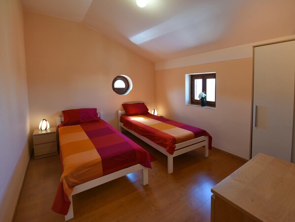 A small, well-lit room with two single beds, a bedside table with a lamp, a window with a view, and a door. - Nice Holiday House With Private Pool & Roof Terrace (Visnjan)
