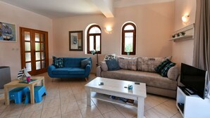 A living room with two sofas, a coffee table, a TV on a stand, and a door with frosted glass panels. - Nice Holiday House With Private Pool & Roof Terrace (Visnjan)