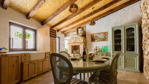 A rustic kitchen with wooden cabinets, a stone wall, and a dining table set for four. - Large Holiday Home With Private Pool, Wellness & Sea View (Vinodol)
