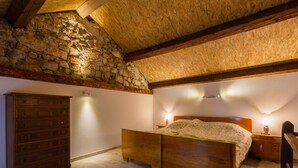 A bedroom with a stone wall, wooden bed frame, and a dresser. - Large Holiday Home With Private Pool, Wellness & Sea View (Vinodol)