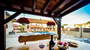 Une table en bois avec une bouteille de vin, un verre de vin rouge et un vase de fleurs.