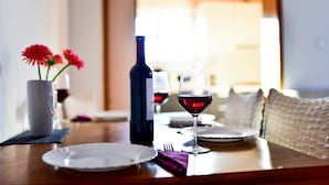 Une table à manger dressée avec des assiettes, un verre à vin, une bouteille et un vase rempli de fleurs.
