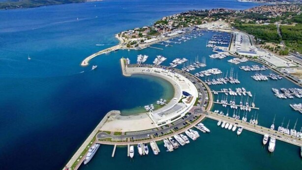 An aerial view of a marina with numerous boats docked, a curved breakwater, and a coastal town in the background. - Apartment in Bibinje With Adriatic Views (Bibinje)