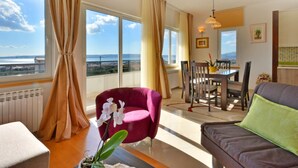 Ein geräumiges Wohnzimmer mit großem Fenster, Essbereich und Meerblick.