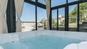 Ett bubbelbad med fri utsikt över omgivningen genom stora fönster.