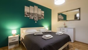 Ein modernes Hotelzimmer mit Bett, Nachttischen, einem Schminktisch und einem Stadtbild an der Wand.