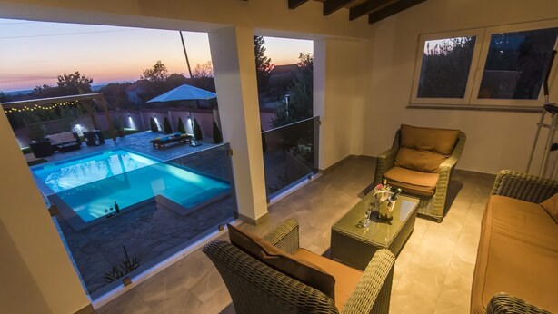 Eine moderne Außenpatio mit Korbmöbeln, einem Pool und Blick auf den Sonnenuntergang.