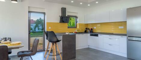 Una cocina moderna con una isla central, armarios blancos y un refrigerador de acero inoxidable.
