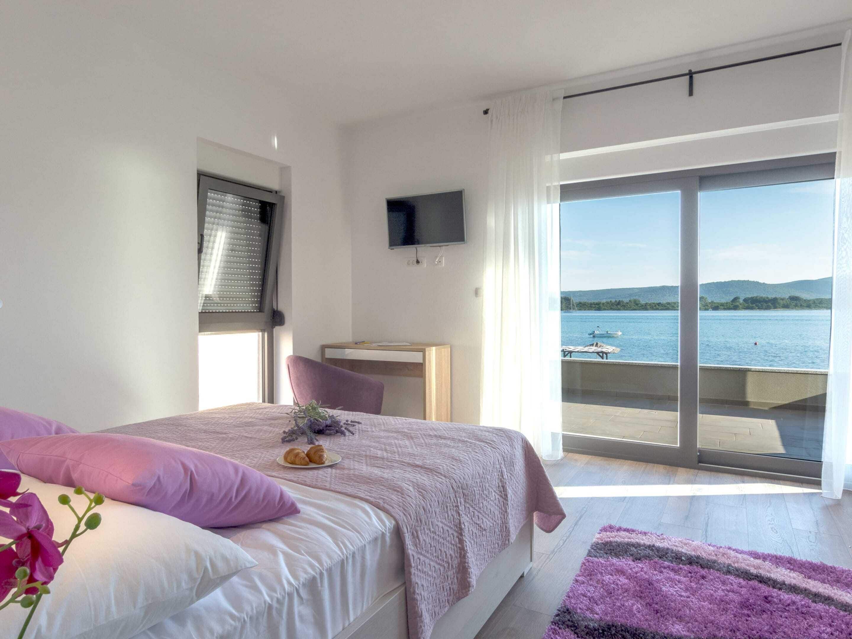 Une chambre avec un lit, un bureau, une télévision et une vue sur un lac.