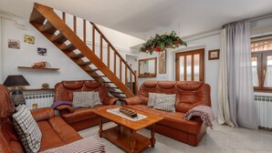Un salon avec un escalier en bois, des canapés en cuir, une table basse en bois et un miroir au mur.