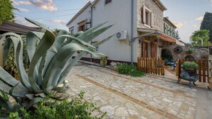 Une maison à deux étages avec une façade en pierre, une clôture en bois et une allée pavée de pierres.