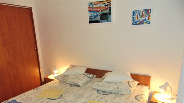 A bedroom with a bed, two bedside tables, a wooden headboard, and two wall-mounted pictures. - Amazing 2 Storey Holiday Home With 120m Roof Terrace, Directly on the Beach (Sveti Filip i Jakov)