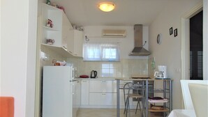 A compact kitchen with a refrigerator, stove, and dining area. - Amazing 2 Storey Holiday Home With 120m Roof Terrace, Directly on the Beach (Sveti Filip i Jakov)