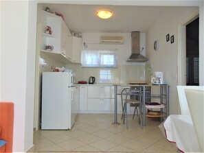 A compact kitchen with a refrigerator, stove, and dining area. - Amazing 2 Storey Holiday Home With 120m Roof Terrace, Directly on the Beach (Sveti Filip i Jakov)