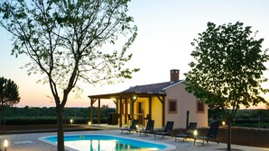 Een huis met een zwembad, buitenzitplaatsen en een pergola.
