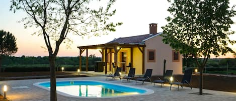A house with a swimming pool, outdoor seating, and a pergola.