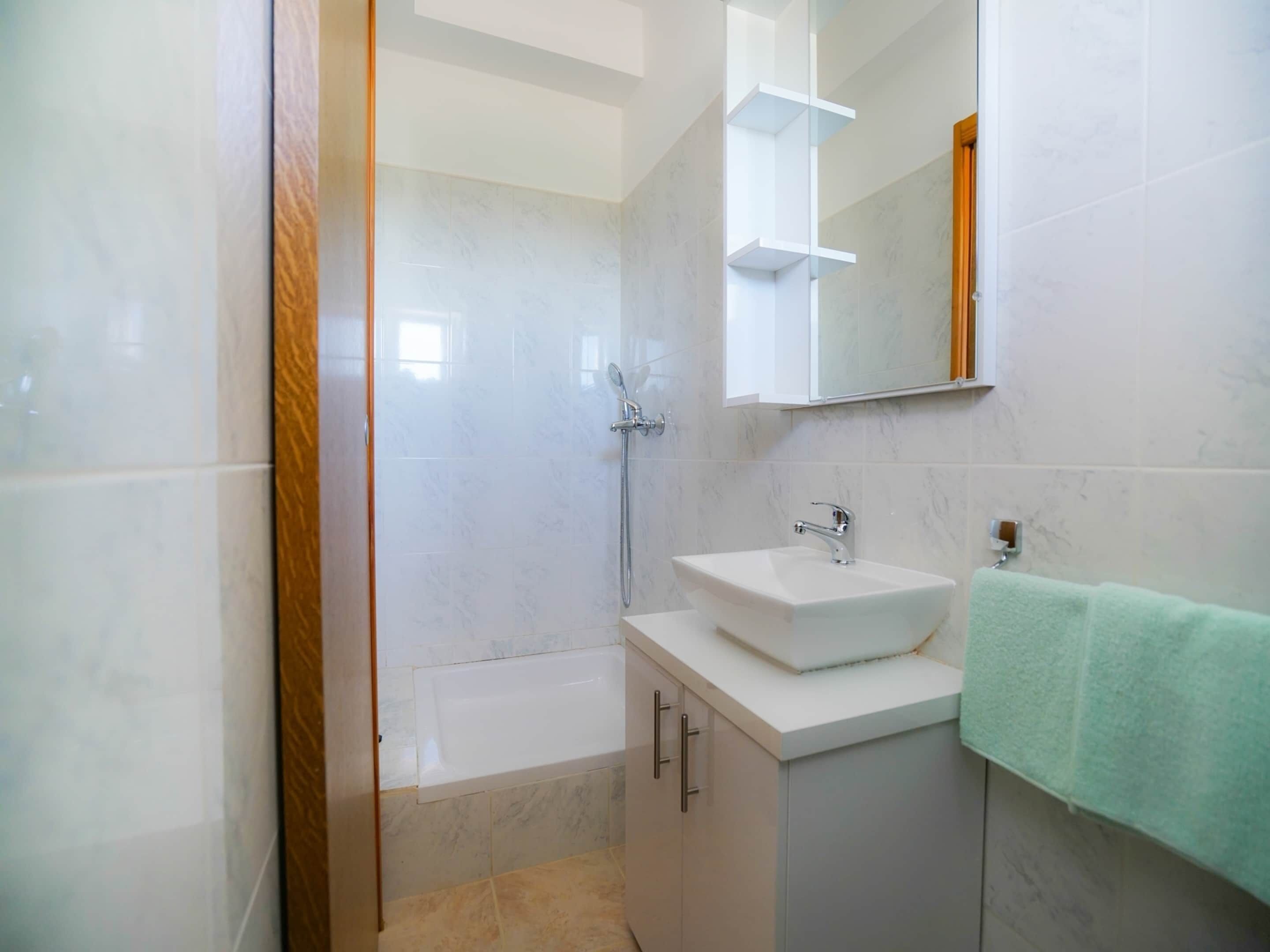 Een badkamer met een bad, een wastafel en een douche.