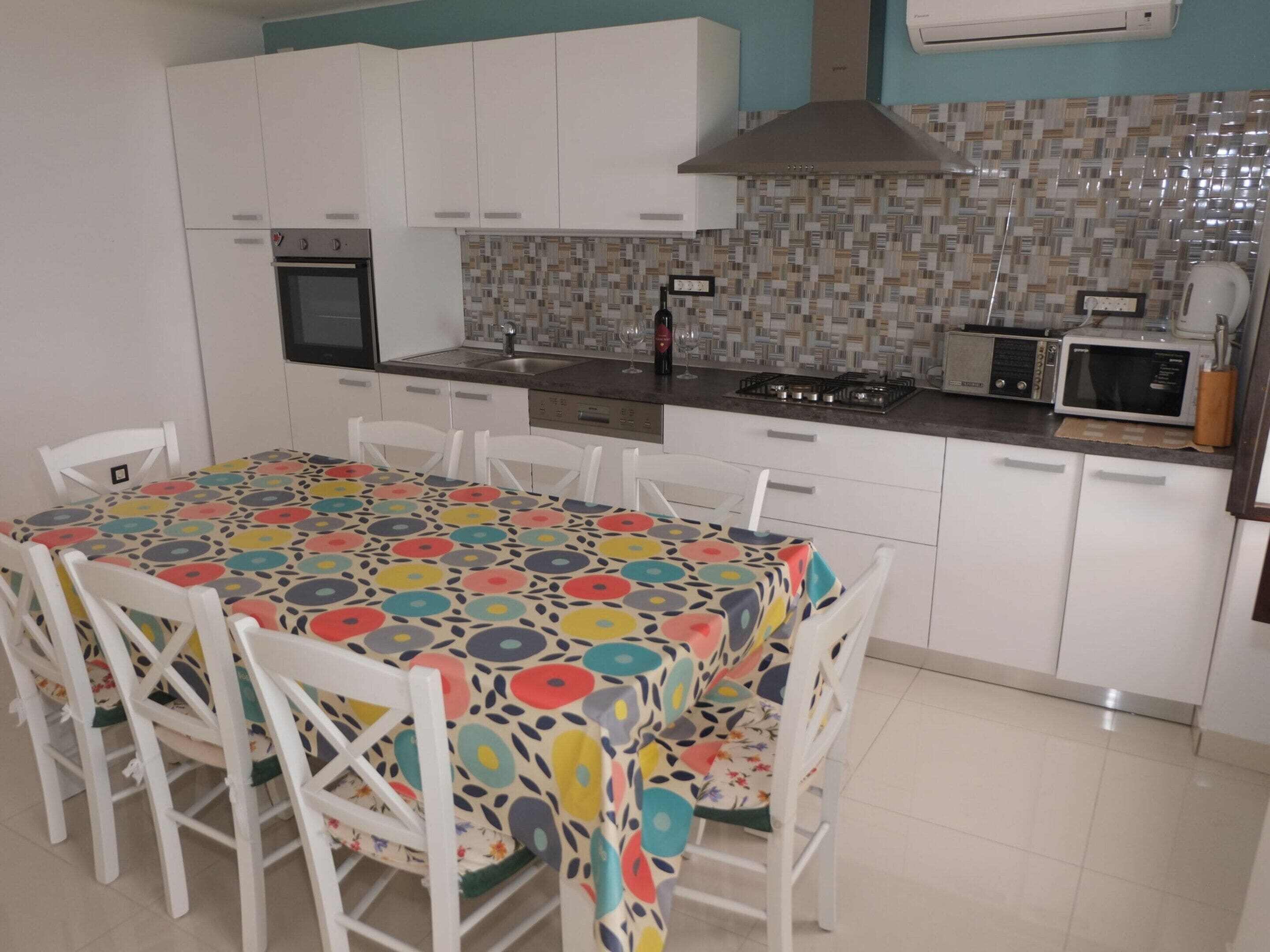 A kitchen with white cabinets, a tiled backsplash, a microwave, and a stove.