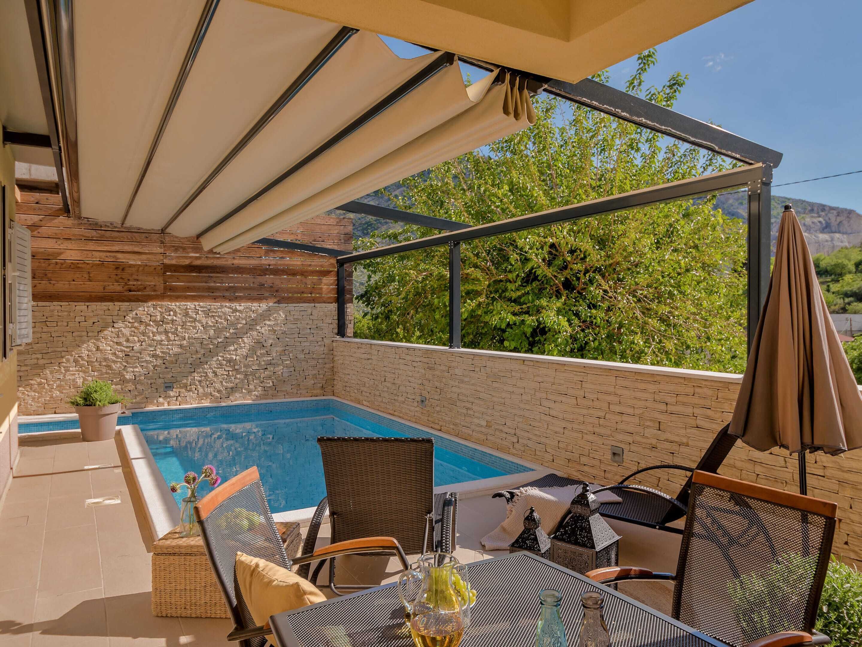 Un espace piscine aménagé sur le toit, offrant une vue sur les arbres et les montagnes, et comprenant des chaises et une table.