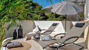 A sunlit outdoor seating area with lounge chairs and an umbrella, surrounded by greenery and a mountainous backdrop. - Luxury Villa Lelu With Heated Saltwater Pool, Parking, High Speed Internet, Bbq, el. car Charge T2 (Split)