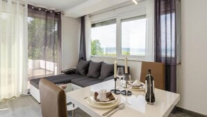 A modern dining area with a table set for two, a sofa, and a view of the outdoors. - Holiday Home in Crikvenica With Sea View (Crikvenica)