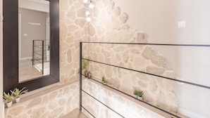 Una escalera con pared de piedra y barandilla metálica.