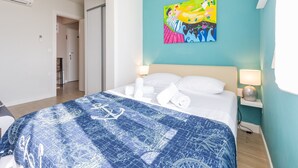 Una habitación de hotel con una cama, un cuadro de colores en la pared y una ventana.