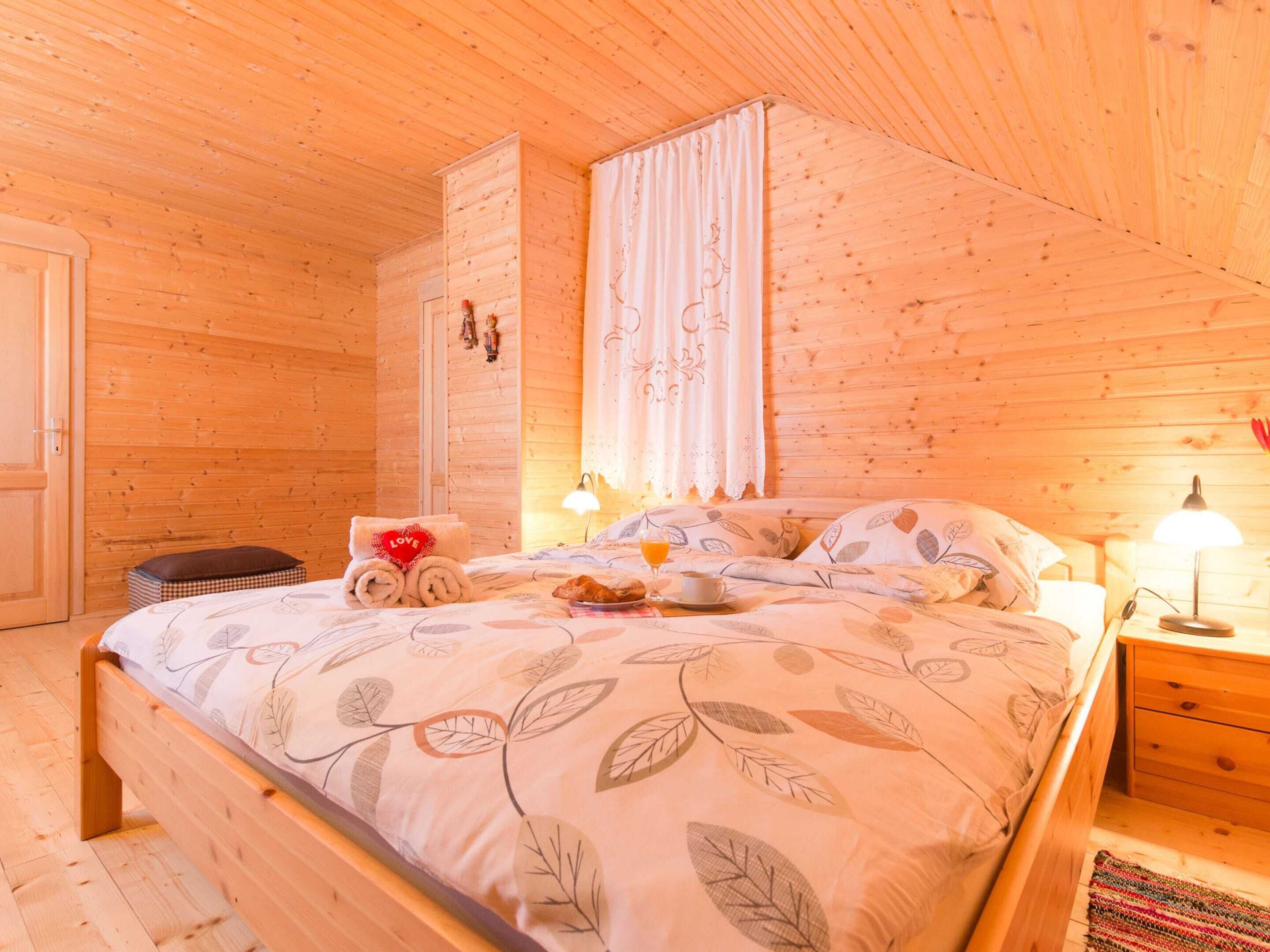 A cozy wooden cabin bedroom with a bed, bedside table, and a nightstand.