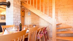 A wooden interior with a dining table set for two, wooden chairs, a staircase, and a stone wall. - Holiday Home Ravna Gora Near Risnjak Park (Ravna Gora)