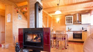 A cozy cabin interior with a wood-burning stove, a dining area, and a kitchen. - Holiday Home Ravna Gora Near Risnjak Park (Ravna Gora)