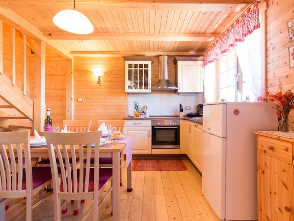 Cozy cabin-style kitchen with a dining table, oven, and stainless steel range hood.