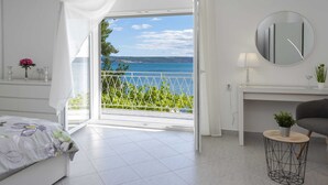 A modern bedroom with a large sliding glass door leading to a balcony with a view of the sea. - Maslenica Pool Villa With Charm (Jasenice)