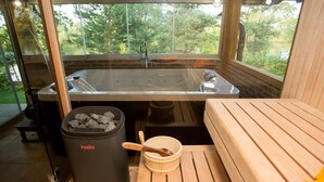 Une salle de sauna avec un banc en bois, une poubelle noire portant l’inscription « helo », et un seau en bois.
