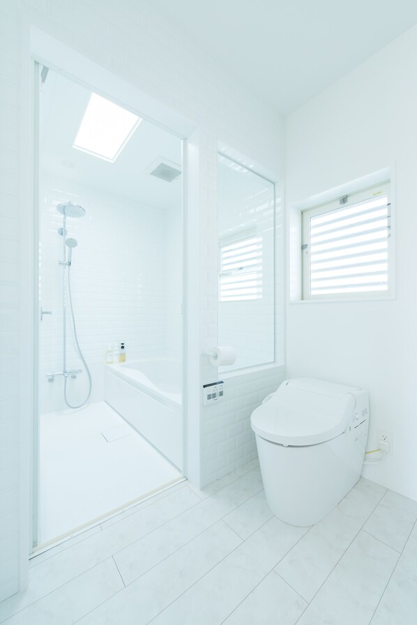 A modern bathroom with a glass shower enclosure, a white toilet, and a large mirror. - Guest Suites Fukugiku (Kyoto)