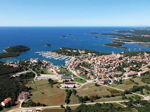 Vue aérienne d’une ville côtière avec un port de plaisance, des zones résidentielles et des champs agricoles.